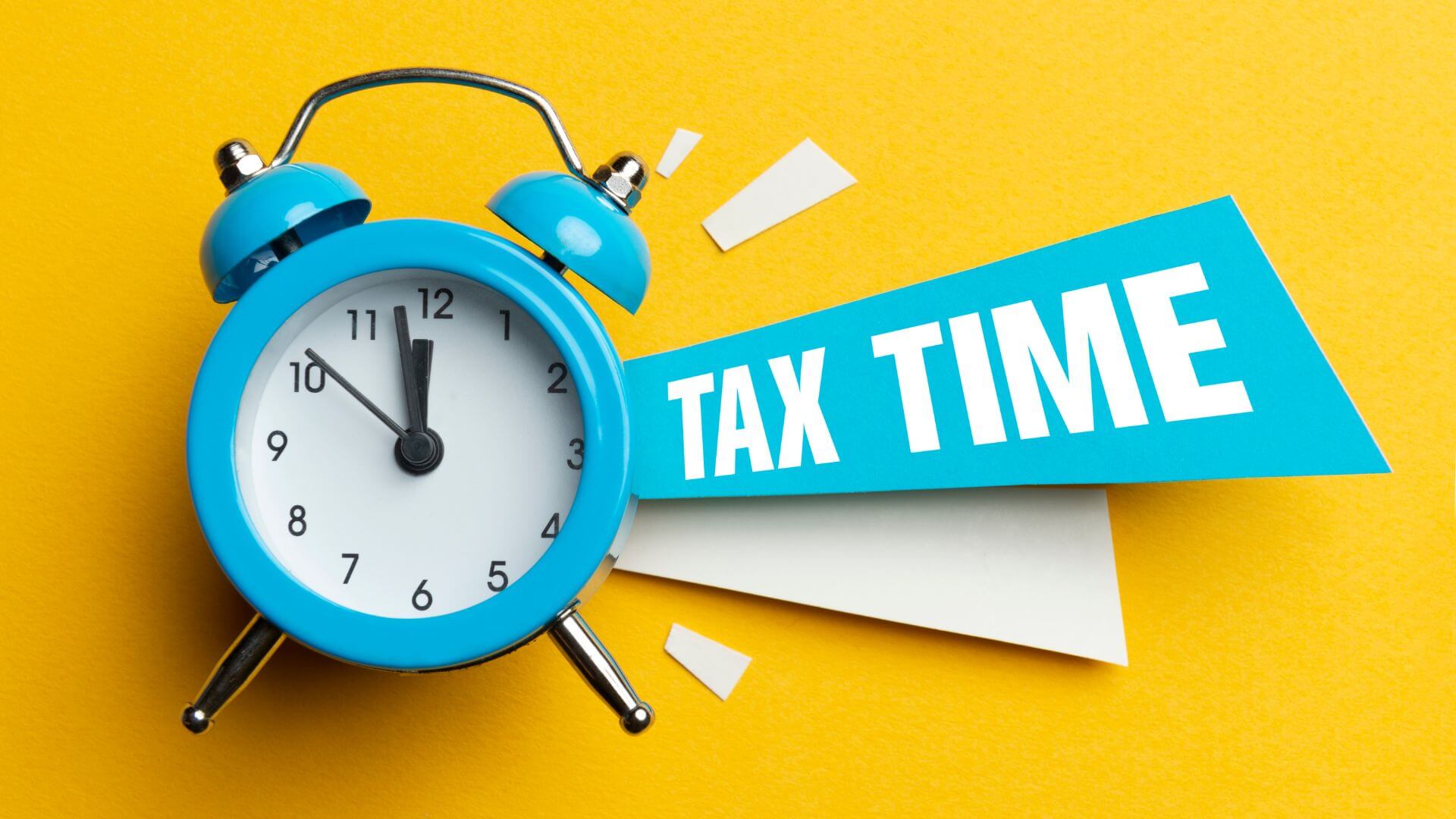 Blue alarm clock with the words 'TAX TIME' on a bright yellow background, symbolizing the urgency and importance of preparing for tax season.