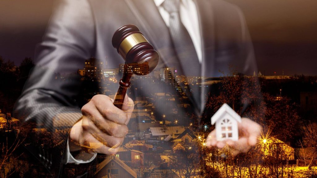 A gavel held by a professional auctioneer with a model house in hand, symbolising the process of preparing a property for auction.