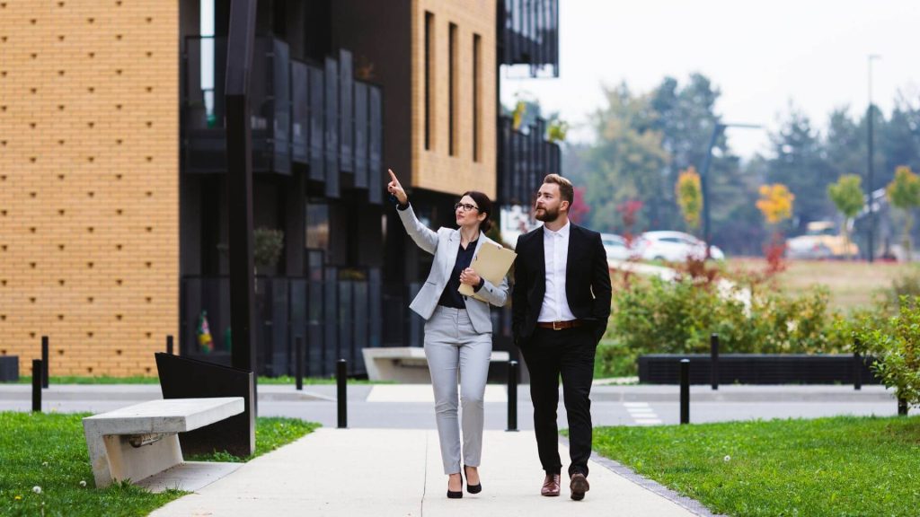 Real estate agent guiding a client through a property, discussing details about selling your investment property.